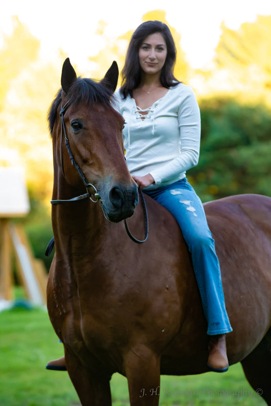 Photo of Lucy Jabrayan sitting on top of a brown horse. 
